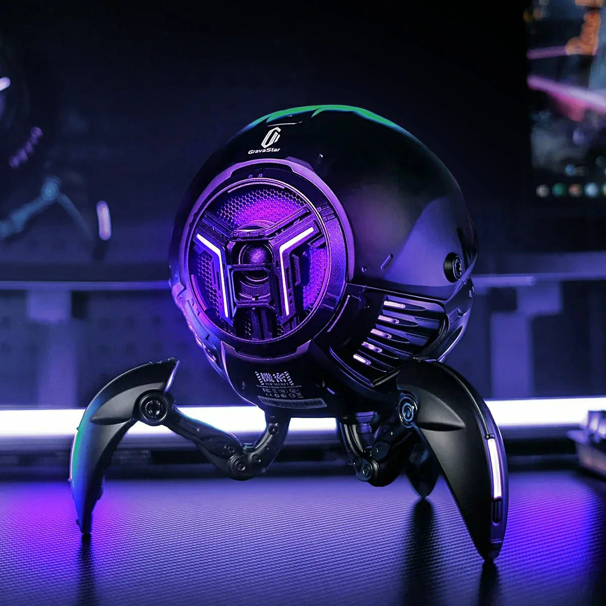 GravaStar Mars Pro sci-fi bluetooth speaker on a gaming desk with purple RGB glow